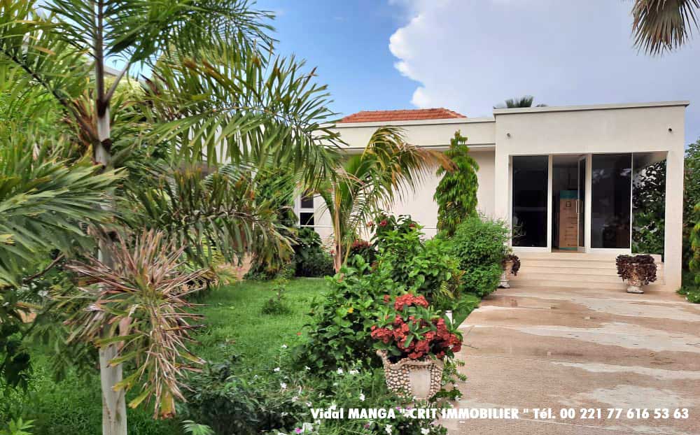 Entrée de la maison bordée de fleurs exotiques, maison de luxe à vendre Cap Skirring proche de la plage et de l'océan immobilier Sénégal